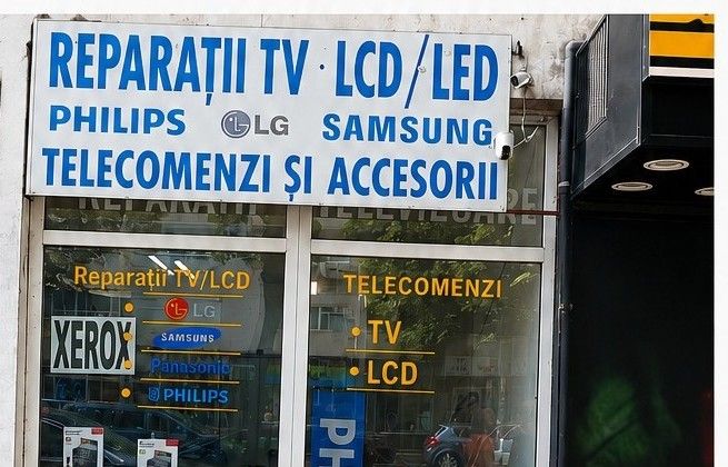 Firma magazinului: Reparații TV LCD / LED, telecomenzi și accesorii, deasupra vitrinei cu telecomenzi TV și LCD