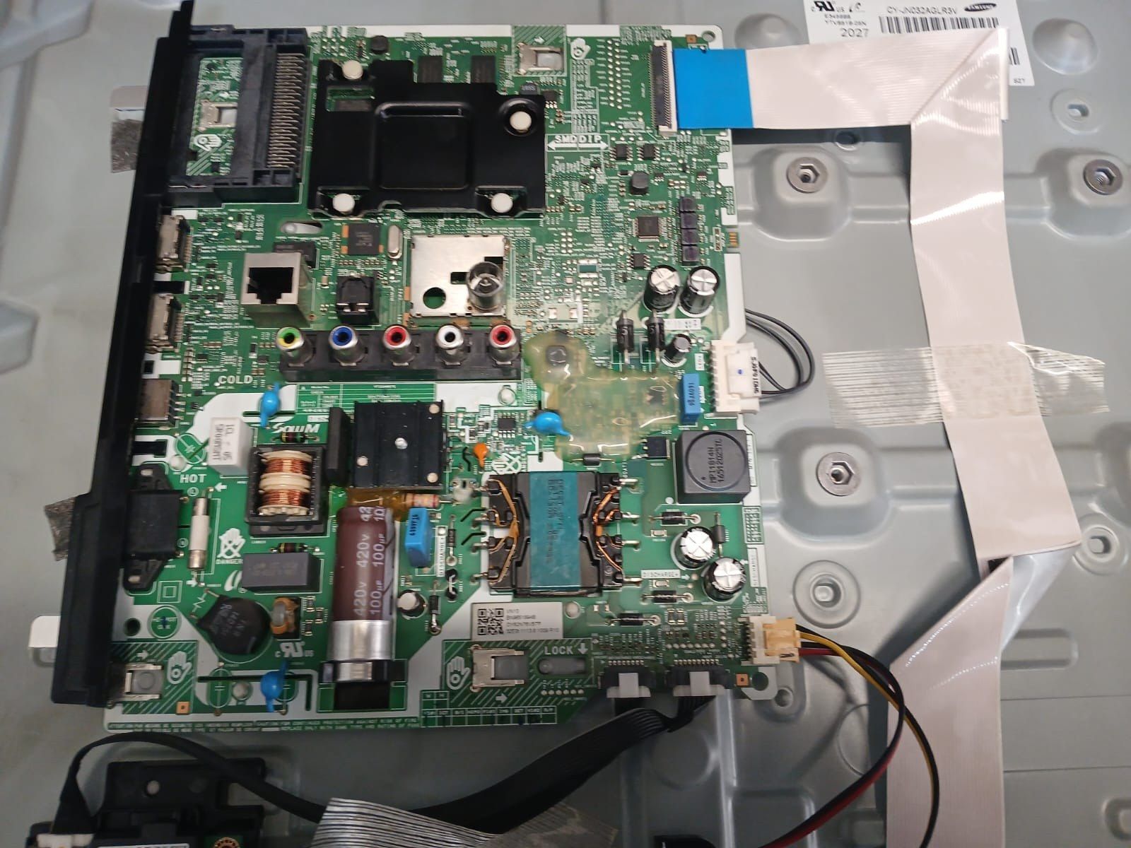 Placa de bază și sursa unui televizor Samsung, demontate pe panoul din spate, cu cablurile panglică și conectorii la vedere